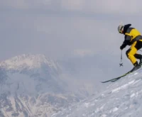 Male adult skier in orange jacket telemark skiing in powder snow in St Anton Austria
