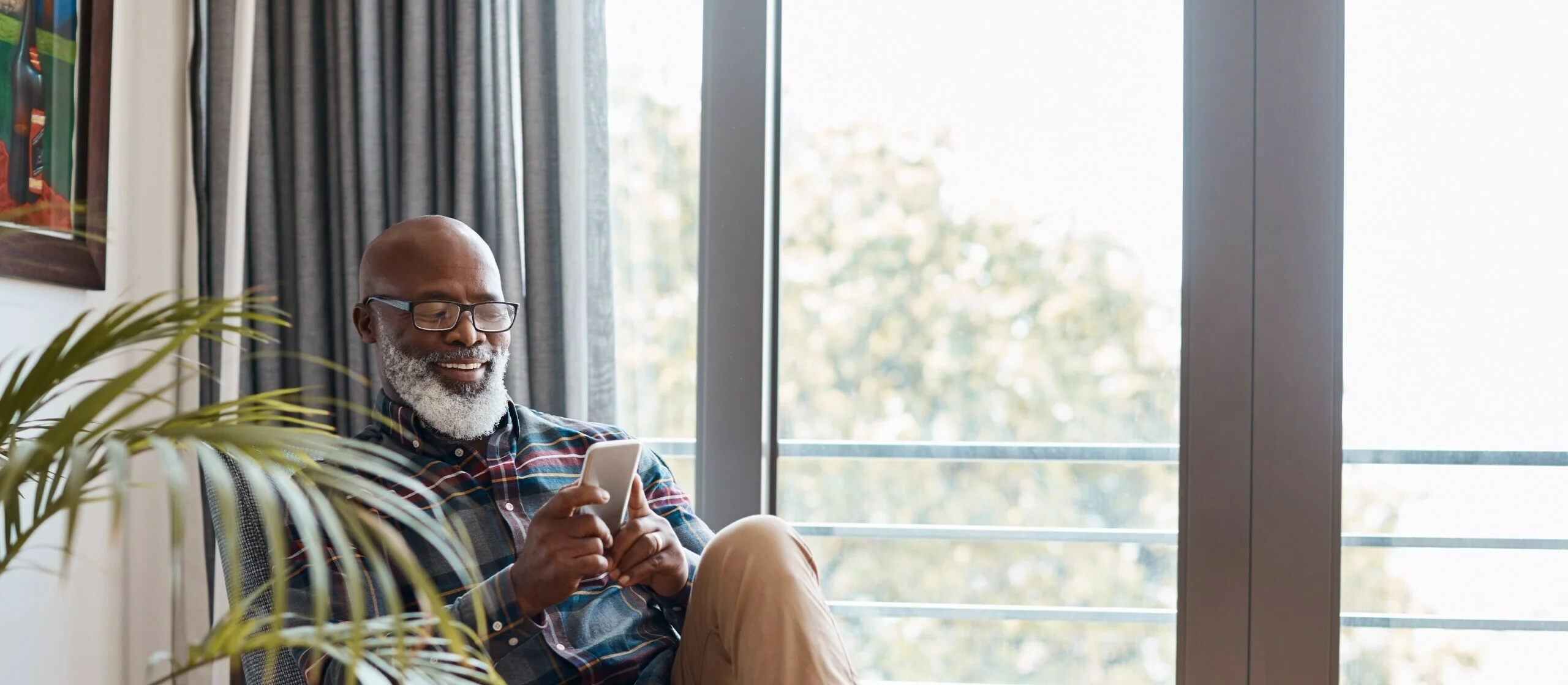 Shot of a mature man using a cellphone while relaxing on a sofa at home