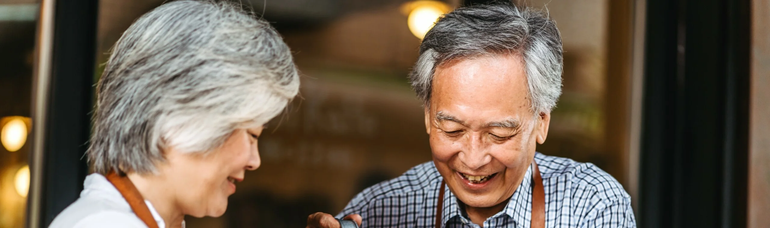 Asian senior couple watering plants in their small garden on the balcony