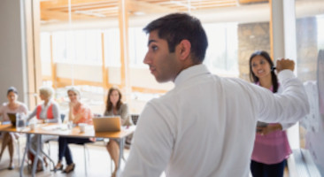 Businessman writing on white board in meeting