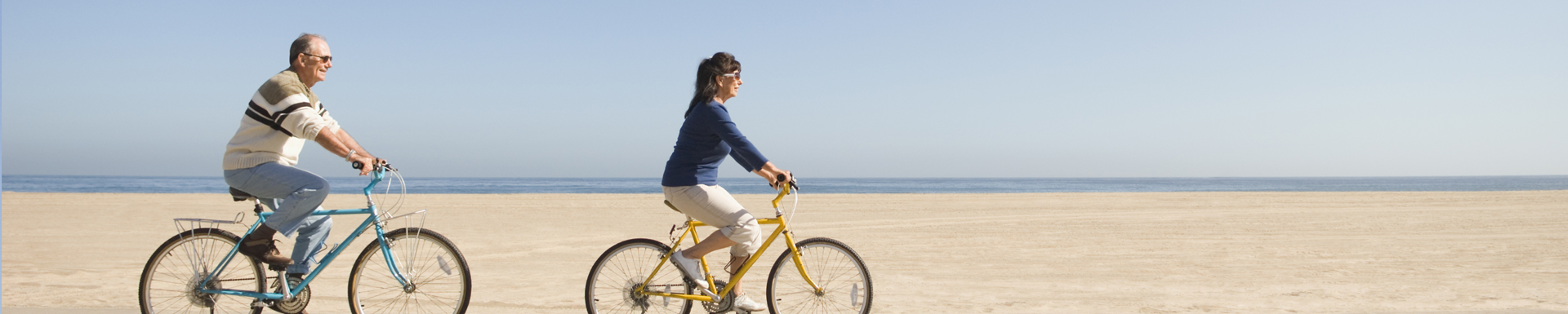 Women riding a bicycle next to the beach