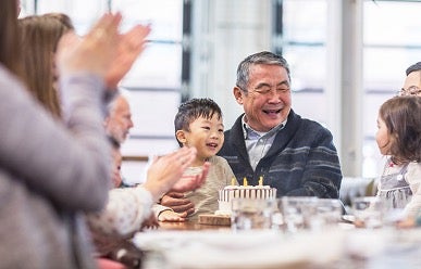 A family with an elderly man enjoying a birthday celebration.