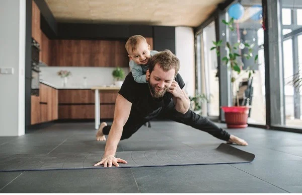 Father doing push-ups with the infant daughter on his back