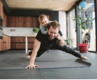 Father doing push-ups with the infant daughter on his back