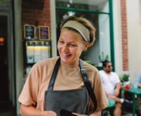 Women in an apron smiling at customers