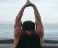 A man practicing yoga on the sea-front