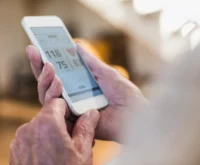 Senior man using smart phone app - close up of hands only. Looking at blood pressure statics.