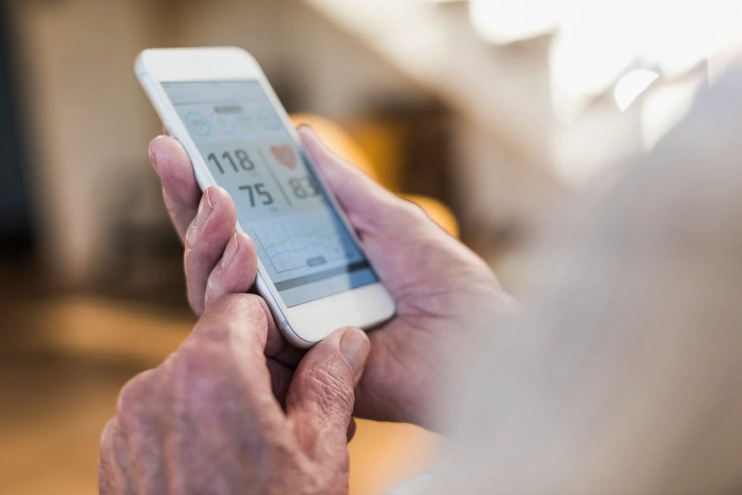 Senior man using smart phone app - close up of hands only. Looking at blood pressure statics.