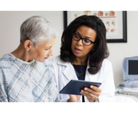 A doctor reviews information with her patient on a tablet
