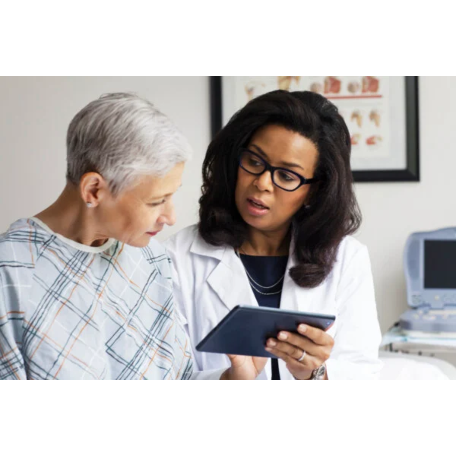 A doctor reviews information with her patient on a tablet