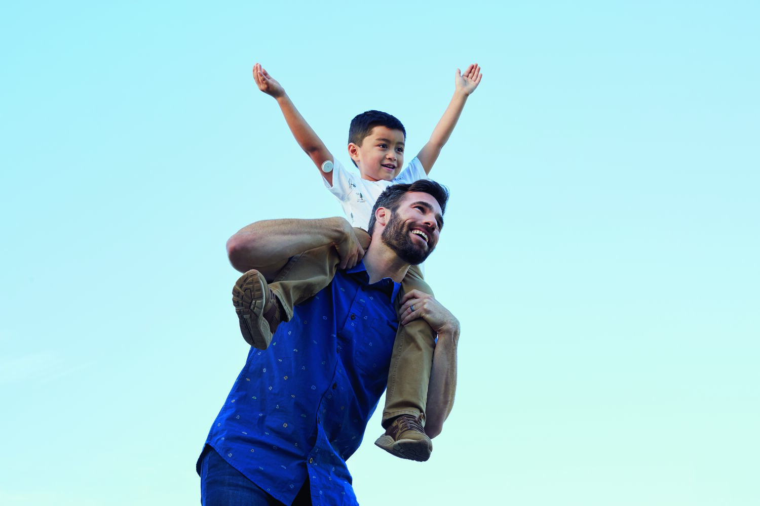 Father carrying his son on his shoulder, playing happily