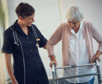 A healthcare professional assisting an elderly woman with walking