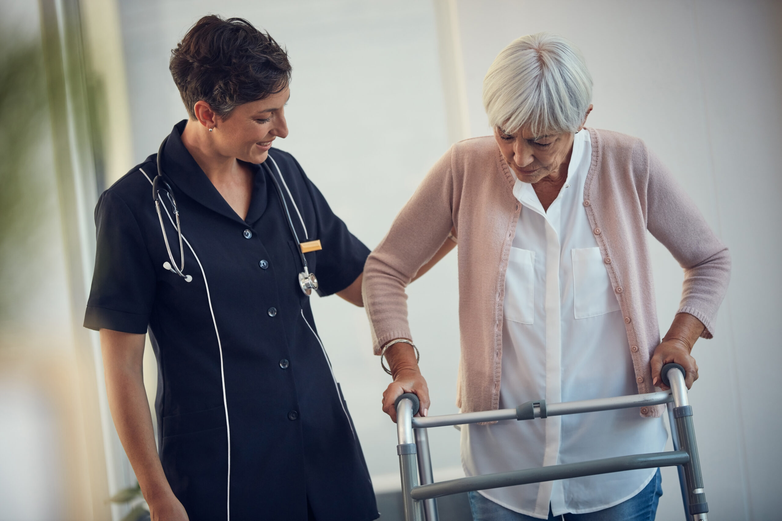 A healthcare professional assisting an elderly woman with walking
