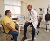 A healthcare professional engaging in a friendly conversation with a patient; a mobile phone on the table.