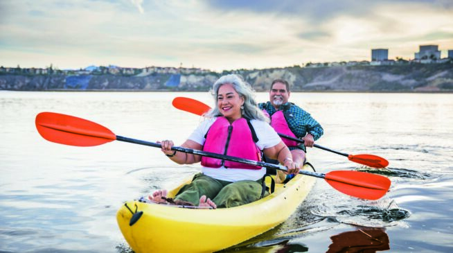 A couple rowing a boat on calm water, embracing their freedom