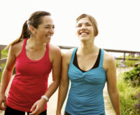 Two young women enjoying a light-hearted conversation on a walk.