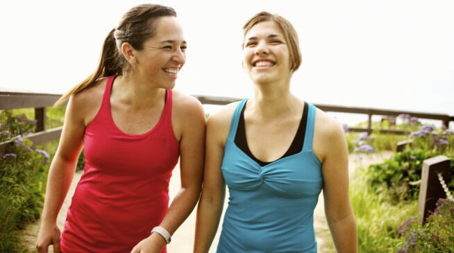 Two young women enjoying a light-hearted conversation on a walk.